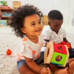 Toddler plays with block toy.