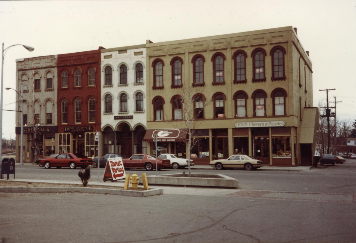 Photograph of the south side of Cross Street showing five businesses, Hon's Flowers and Fancies, Depot Exchange Antiques, Artrain, Framing & Matting and Sidetrack Bar & Restaurant.